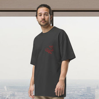 Man wearing a black t-shirt with a red logo in a modern room with large windows.